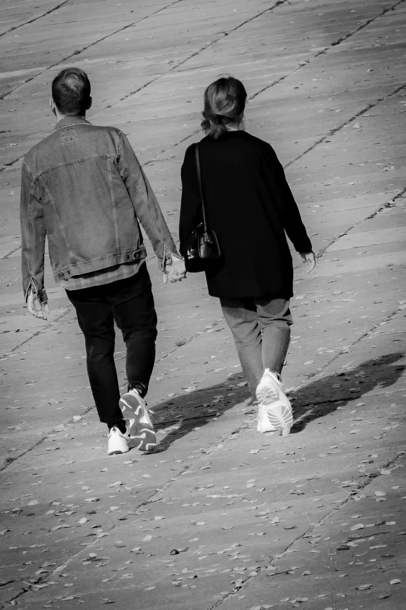 Couple walking away hand in hand on a sloped concrete path